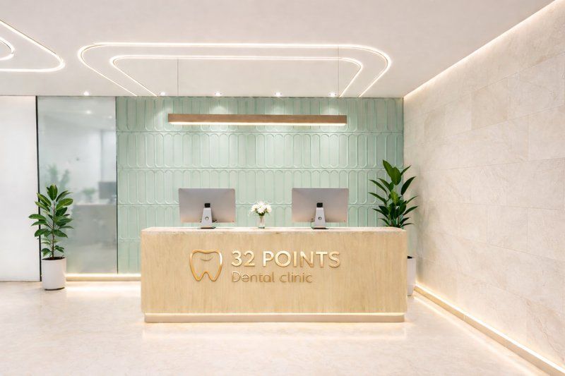 Dental clinic reception with mint green tiled wall, timber desk and 32 Points signage